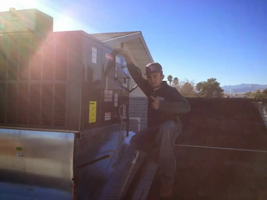 HVAC technician performing AC Tune-Up on a rooftop unit in Artesia